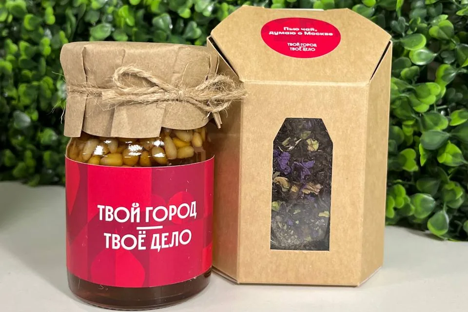 Мёд с кедровыми орешками в банке с фирменной этикеткой «Твой город — твоё дело» и чай в крафтовой коробке с наклейкой