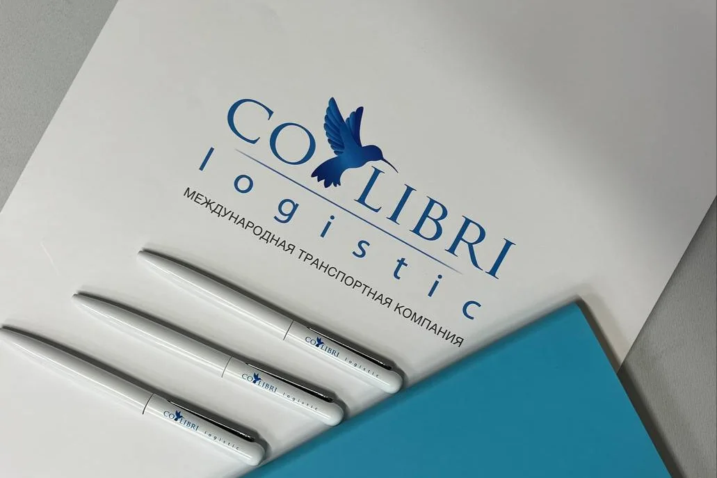 Белый пакет и три белые ручки с логотипом Colibri Logistic, в углу — бирюзовый блокнот