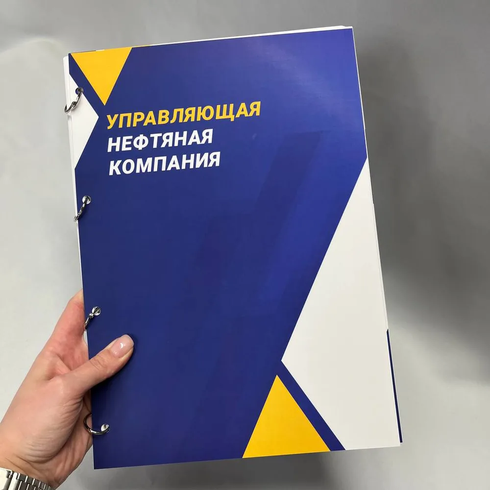 Сине-жёлтая обложка документа на металлических кольцах в руке